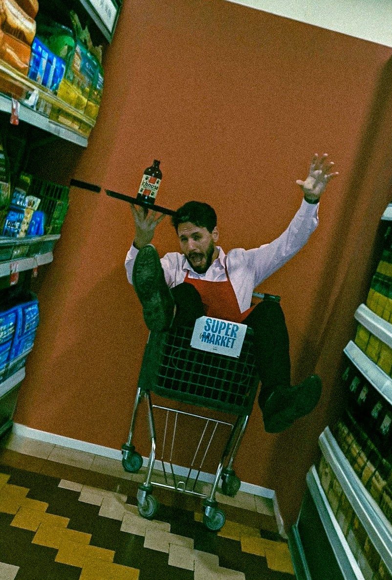 Mattia Di Bello in un carrello della spesa con vassoio e bottiglia, scatto ironico